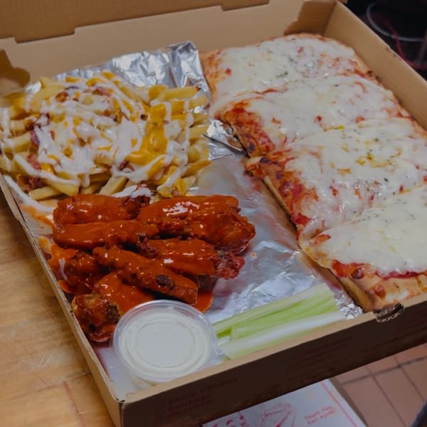 A pizza box filled with cheesy fries, buffalo wings, a side of ranch, and a cheese pizza.